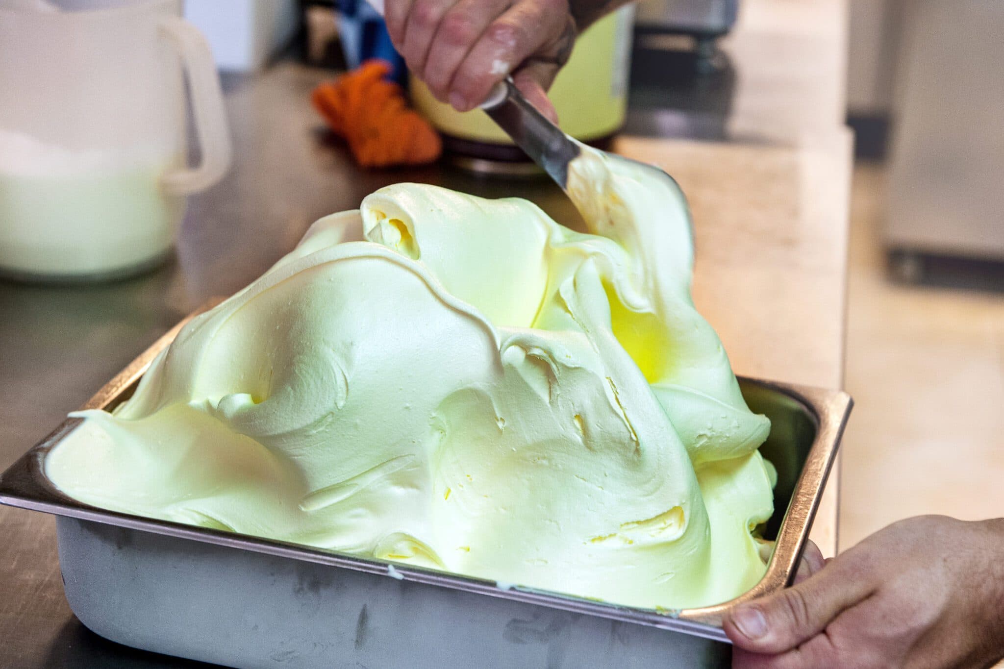Fresh gelato spread by hand into a tub at Baci's Norwood factory